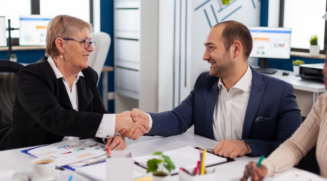 Consultant greeting international client with handshake after partnership